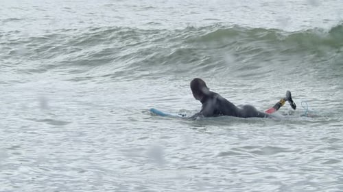 Man with Artificial Leg Paddling in on Surfboard in Ocean