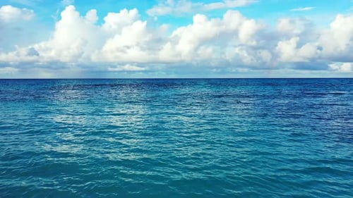 Weitwinkelfliegende Insel mit Blick auf einen paradiesischen sonnigen weißen Sandstrand und aquablauen Ozeanhintergrund