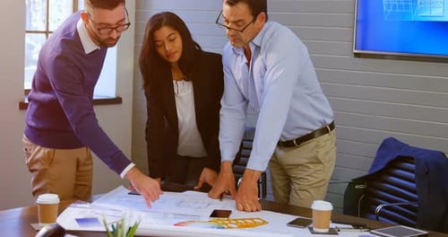 Team Examines Blueprints in Bright Office