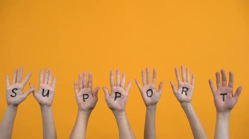 Unterstützen Sie geschriebene Handflächen auf orangefarbenem Hintergrund, Teamwork, Zusammenarbeit