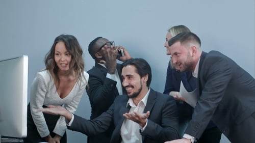 Diverse Team Celebrates Success Around Computer in Office