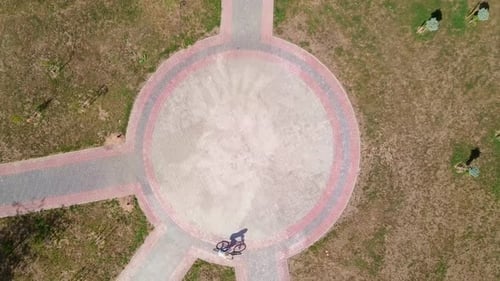 Top view of a bicycle woman riding a bicycle on a circular road in a city park.