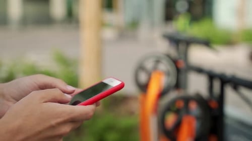 Woman Using Smartphone To Pay for Rental Electric Scooter While Standing on Parking Lot on Modern