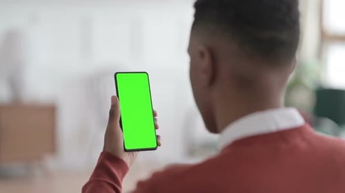 Rear View of African Man Looking at Smartphone with Green Chroma Screen