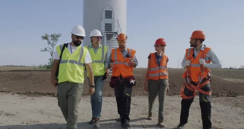 Group of Engineers Walking and Talking on Wind Farm