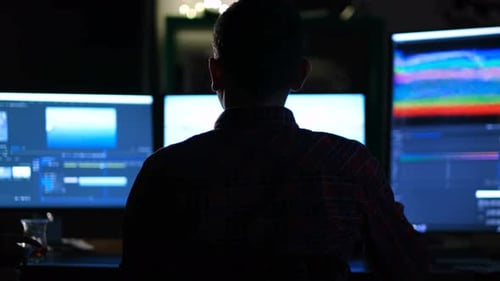 Person Editing Video at Computer Workstation at Night