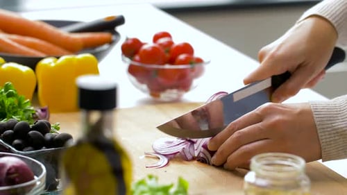 Hands Cutting Red Onion Amongst Fresh Vegetables