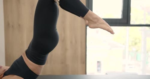 Woman Exercises on Pilates Reformer Machine in Studio