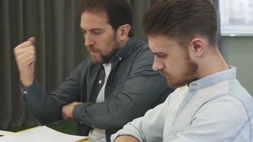 Handsome Bearded Young Man Talking To His Mature Colleague at the Office
