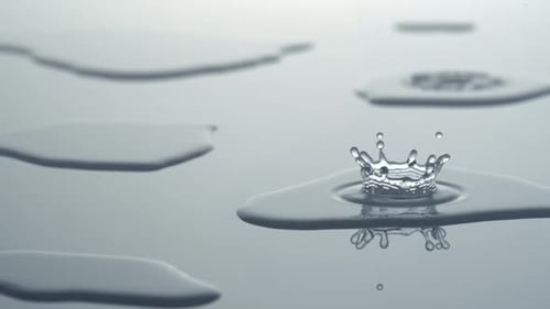 Water Droplets Creating Ripples on Reflective Surface