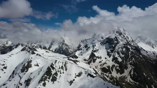 Air Flight Through Mountain Clouds Over Beautiful Snowcapped Peaks of Mountains and Glaciers