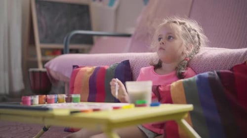 Girl Sits Indoors and Paints at Table