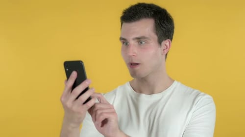 Young Man Smiling While Looking at Smartphone