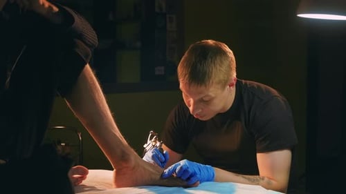 Master Artist with Old School Coil Machine Colors Foot Tattoo on Customers Leg