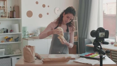 Woman Kneading Dough in Bright Kitchen with Camera