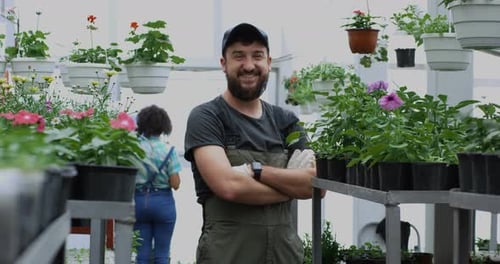 Bearded Man Smiles in Bright Greenhouse with Flowers