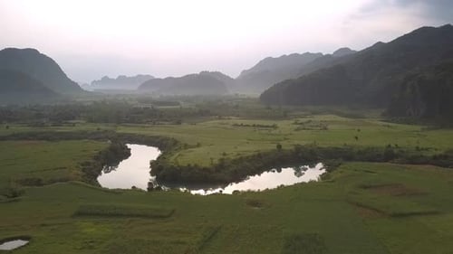 Green Vast Field Near Calm River Reflecting Yellow Sun Rays
