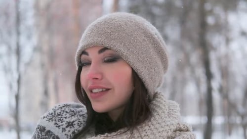 Portrait of a Beautiful Girl in a Hat with Dark Hair Stands in the Winter in the Park in Snowy