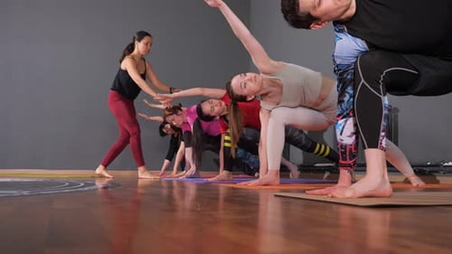 Yoga Class Practices Pose in Bright Studio