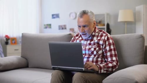Mature Man Celebrating While Using Laptop at Home