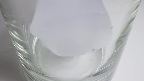 Ice Cubes Fall Down Into Empty Glass for Cocktail on Table