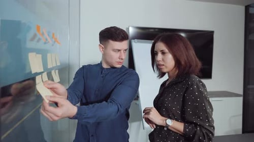 Multiethnic Managers Arranging Sticky Notes on Agile Board in Office