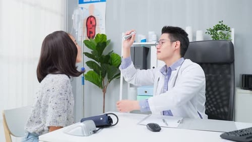 Asian specialist male doctor examine and use flashlight on patient eye in hospital.