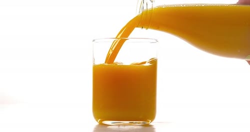 Orange Liquid Pouring Into a Glass