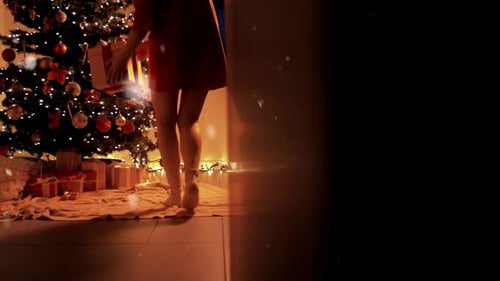 Woman Placing Gifts under Christmas Tree with Snowfall