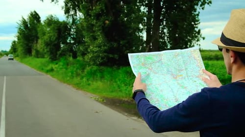 A Man Looks at a Map on the Road