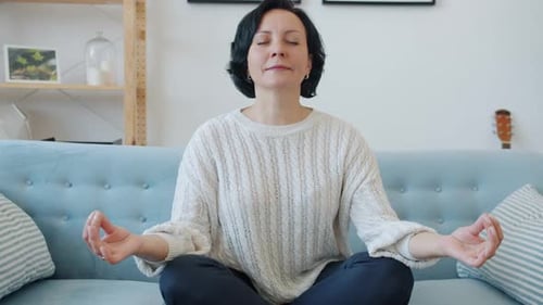 Woman Meditating on Couch in Bright Living Room