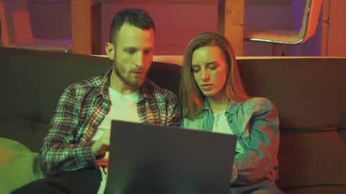 Young Couple Using Laptop on Sofa at Home