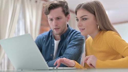 Joyeux jeunes collègues designers travaillant sur un ordinateur portable