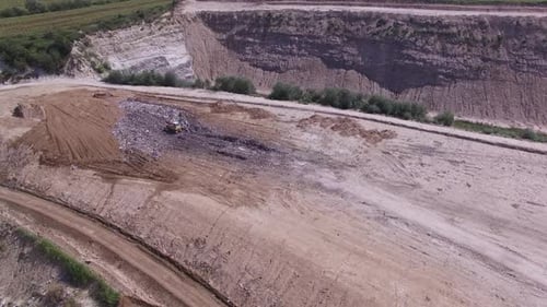 Birds Fly Aroud Garbage Pile on Junkyard Near Working Excavator