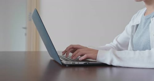 Woman Typing on Laptop at Table Indoors