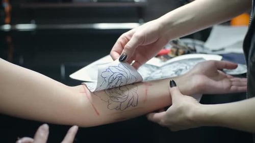 Tattoo Artist Applying Stencil to Client's Arm