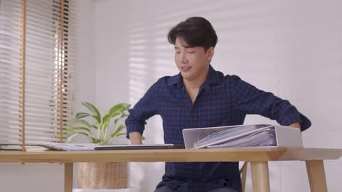 At home, a business asian man types and works online on a desk table with a laptop.