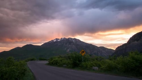 Sunrise time lapse looking at mountain and colorful clouds down road