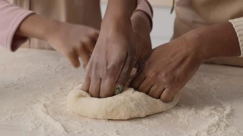 Close Up Shot of Unrecognizable African American Mother and Daughter Kneading Raw Dough on Kitchen