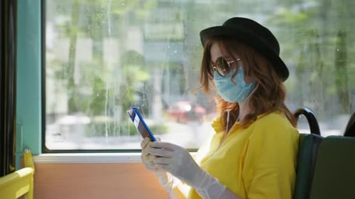 Young Woman Rides Bus with Mask and Smartphone