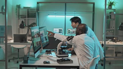 Scientists Collaborate Using Computers and Microscopes in Office