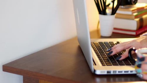 Woman using a laptop while having cup of coffee