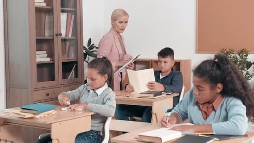 Female Teacher Checking Students Works in Class