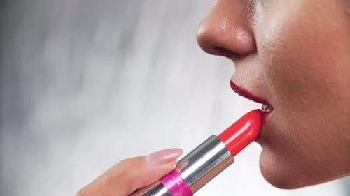 Woman Applying Vibrant Red Lipstick Close Up