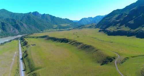 Aerial Rural Mountain Road and Meadow at Sunny Summer Morning. Asphalt Highway and River.