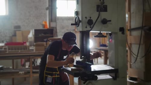 Carpentry Workshop Worker Prepares the Automatic Saw for Cutting a Wooden Board