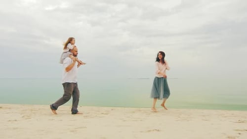 Happy Family of Three People Running on the Beach. Fun Games with Children
