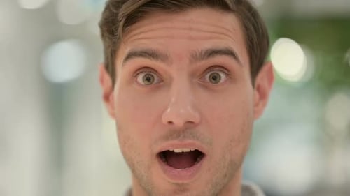 Nahaufnahme eines schockierten Ausdrucks eines kreativen jungen Mannes