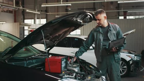 Mechanic with Tablet Diagnosing Car Problem in Shop