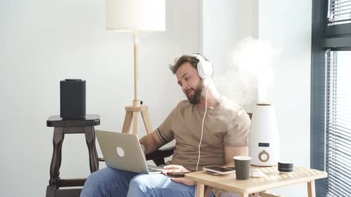 Man Working on Laptop at Home with Humidifier